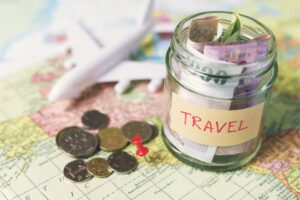 Collecting money for travel, money savings in a glass jar with world map