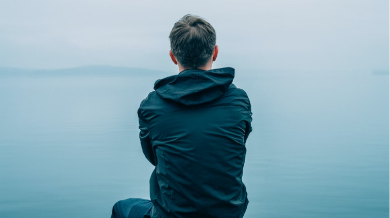 A teen boy sitting alone feeling sad.