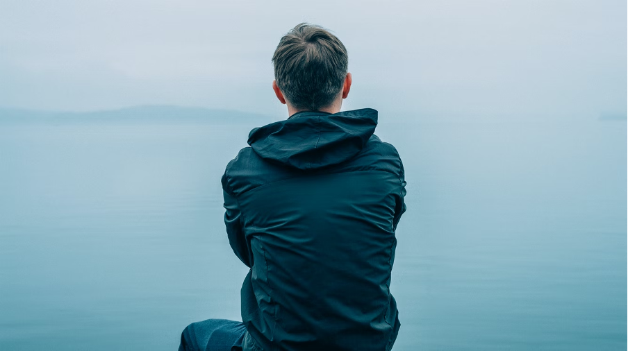 A teen boy sitting alone feeling sad.