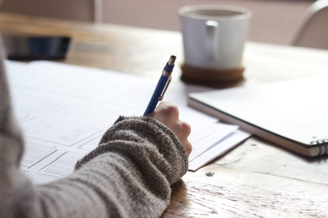 A woman writing with a pen in her book.