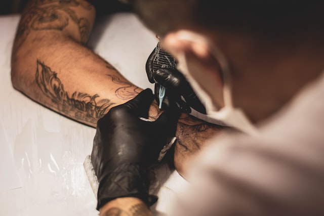 A man removing the tattoo with a needle.