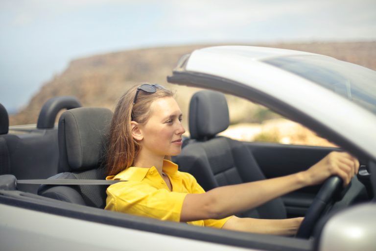 A woman driving a white car.