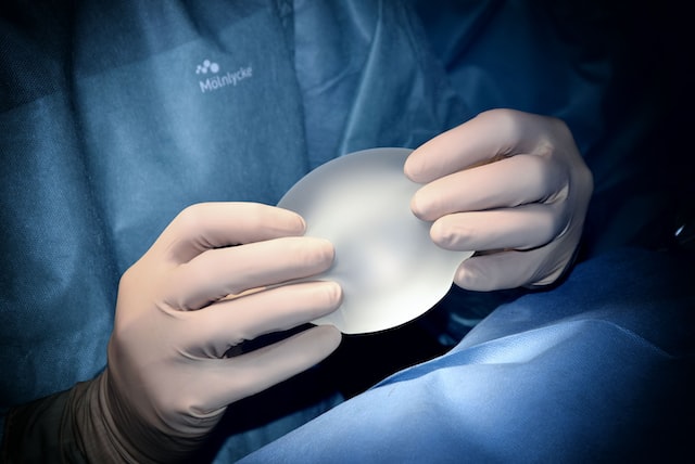 A surgeon holding a plastic piece in his hand for surgery.