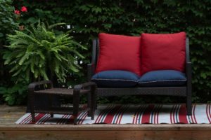 A lawn chair and sofa with cushions placed in the outdoor garden area.