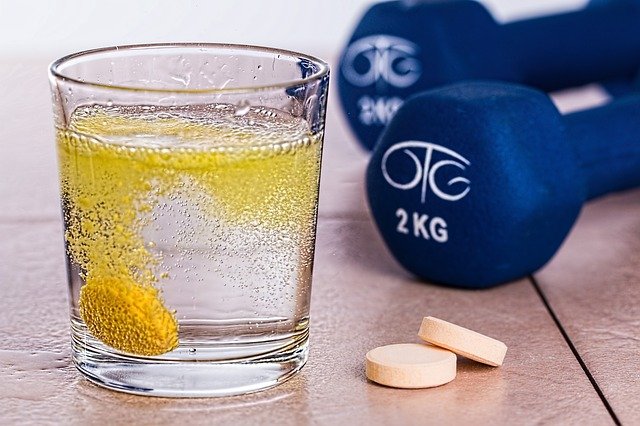vitamin b g66b9acd80 640 A glass of water with supplements and dumbles.
