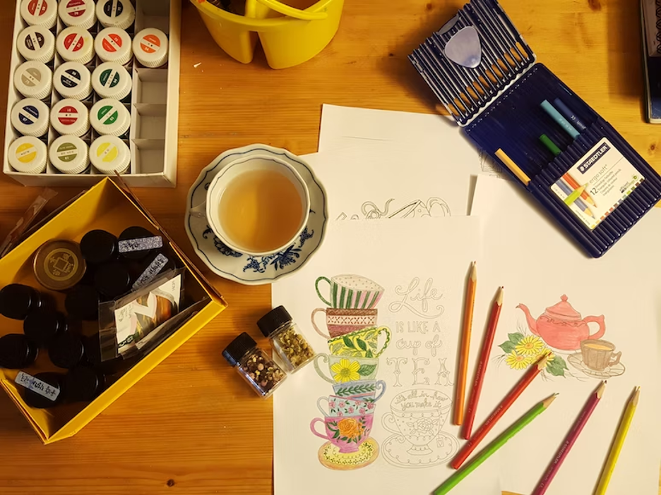 Drawing sheets, pencils, and paints are placed on a table.