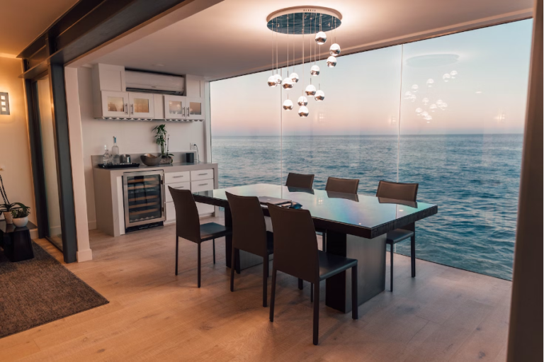 A living room with a layered lamp and dining table facing the sea.