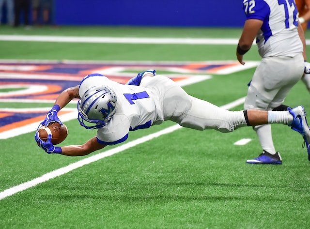 A man falling while holding the Football.