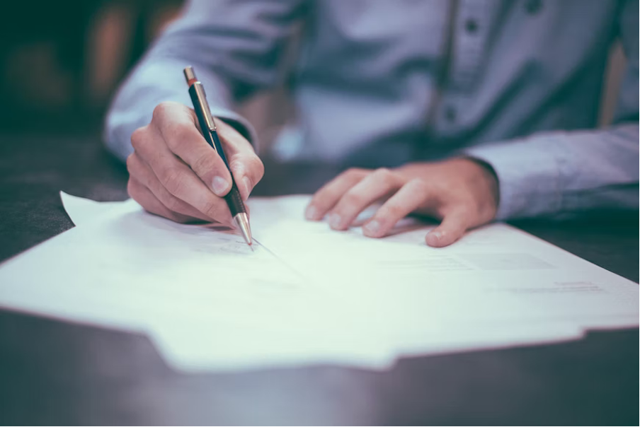 Picture 1 A man signing a document.